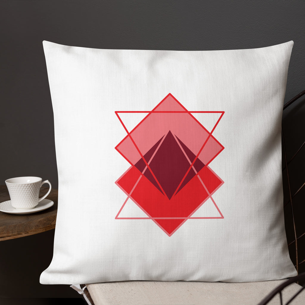 Ein Dekokissen der Grundton ist cremeweiß ist mit einem minimalistischen abstrakten Motiv aus überlappenden, roten und rosafarbenen geometrischen formen in der Größe 22"x22".