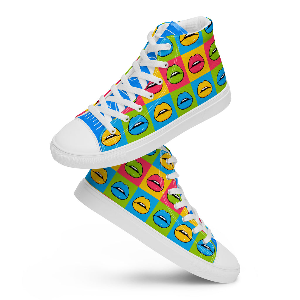 Zwei schwebende, weiße High-Top Canvas Schuhe mit einem bunten Pop-Art-Muster, das wiederholende Lippenpaare in Gelb, Blau und Pink auf verschiedenfarbigen Quadraten (Blau, Grün, Pink, Gelb) zeigt. Die Schnürsenkel und Sohlen sind weiß. Die Schuhzungen sind blau, mit "Kiss" auf der linken und "Me" auf der rechten Zunge in weißer Schrift. Designed, by Just a Girl.